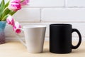 Black coffee cup and white latte mug mockup with magenta tulip