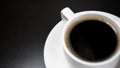 Black coffee drink. A white cup of black coffee on plate on dark table background. Morning coffee. Royalty Free Stock Photo