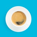 Black coffee with foam in a white cup on plate, top view, at blue background Royalty Free Stock Photo