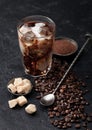 Black coffee with ice cubes and fresh milk with beans and cane sugar with ground coffee and long spoon on black Royalty Free Stock Photo