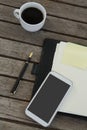 Black coffee, mobile phone and office supplies on wooden plank Royalty Free Stock Photo