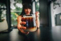 Black coffee in a modern glass on the hand of a girl in cafe