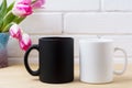 Black coffee mug and white cappuccino cup mockup with pink tulip Royalty Free Stock Photo