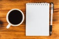 Black coffee with notepad and pen on wooden table surface Royalty Free Stock Photo