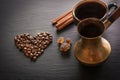 Black coffee in old copper cezve and cup and coffee beans on black slate as background with copy space. Royalty Free Stock Photo