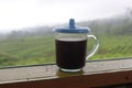 The black coffee in the tea garden is shrouded in mist. a cup of black coffee in a mountainous area. enjoy coffee in the mountains