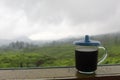 The black coffee in the tea garden is shrouded in mist. a cup of black coffee in a mountainous area. enjoy coffee in the mountains