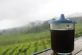 The black coffee in the tea garden is shrouded in mist. a cup of black coffee in a mountainous area. enjoy coffee in the mountains
