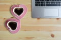 Black coffee in two pink cups heart shape and laptop computer on wooden floor, Copy space or empty space for text