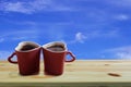 Black coffee in two pink cups heart shape on wooden floor and blue sky background, Copy space or empty space for text