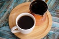 Black coffee in a white cup and copper cezve on round bamboo stand. Traditional turkish method