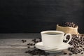 Black coffee in a white coffee cup with hot steam and coffee beans placed on a wooden table on a dark background. in a warm Royalty Free Stock Photo