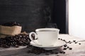 Black coffee in a white coffee cup with hot steam and coffee beans placed on a wooden table on a dark background. in a warm Royalty Free Stock Photo