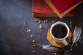 Black coffee in white cup and old books with feather and dried flower petals.