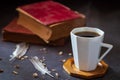 Black coffee in white cup and old books with feather and dried flower petals.