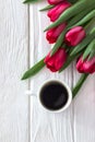 Black coffee in a white cup and red tulips on a white background. Top view, free space Royalty Free Stock Photo