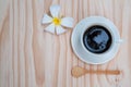 Black coffee in white cup with white plumeria flower on wooden b Royalty Free Stock Photo