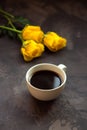 Black coffee in a white cup and yellow roses on a dark background Royalty Free Stock Photo