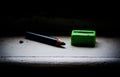 Black color pencil with the old green pencil sharpener, the image in dark tone light. Royalty Free Stock Photo
