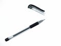 Black colored ball point pen and its cap scattered on top of a white background Royalty Free Stock Photo