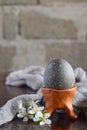 Black colored egg on clay plate. Happy Easter card. Holidays breakfast concept. Festive table place setting decoration Royalty Free Stock Photo