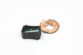 Black colored plastic pencil sharpener and a piece of pencil shavings placed beside one another Royalty Free Stock Photo