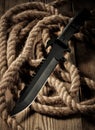 Black combat military knife on wooden table.