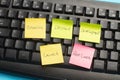 Black computer keyboard and colored paper notes with words on a blue background Royalty Free Stock Photo