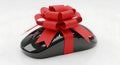 Black computer mouse adorned with a festive red ribbon and bow Royalty Free Stock Photo