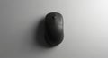 A black computer mouse is centered on a smooth, light gray surface. The mouse has Royalty Free Stock Photo