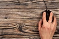 Black computer mouse with a hand on a black wooden background with copy space for your text. Top view Royalty Free Stock Photo