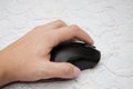 Black computer mouse in hand on a wooden background. Close-up. Royalty Free Stock Photo