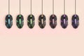 Black computer mouses hang on pastel peach background