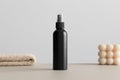 Black cosmetic spray bottle mockup with a candle and a towel on the beige table Royalty Free Stock Photo