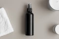 Black cosmetic spray bottle mockup with a towel on the beige table Royalty Free Stock Photo