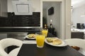 Black countertop of a kitchen with breakfast and orange juice, Royalty Free Stock Photo