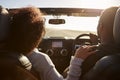 Black couple driving, her hand on his shoulder, back view