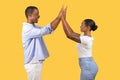 Black couple high-fiving, joyful moment on yellow background Royalty Free Stock Photo