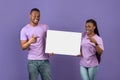 Black couple holding and pointing at blank white advertising placard Royalty Free Stock Photo