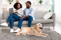 Black couple at home using laptop sitting with dog Royalty Free Stock Photo