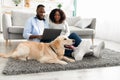 Black couple at home using laptop sitting with dog Royalty Free Stock Photo