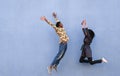 Black couple jumping outdoor with blue wall in background - Crazy happy african friends having fun together - Youth, friendship Royalty Free Stock Photo