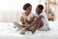 Black couple in love sitting on bed and talking Royalty Free Stock Photo