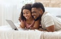 Black couple in love surfing internet together, lying on bed Royalty Free Stock Photo