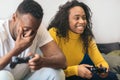 Black couple playing video game at home. The man loosing with disappointed face and the girl with happy face Royalty Free Stock Photo