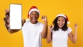 Black couple in santa hats showing white empty smartphone screen Royalty Free Stock Photo