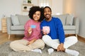 Black Couple Showing Credit Card And Piggybank With Savings Indoors