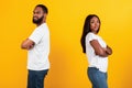 Black couple standing back to back, yellow studio wall Royalty Free Stock Photo