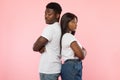 Black couple standing back to back, pink studio wall Royalty Free Stock Photo