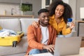 black couple using laptop and credit card buying tickets indoor Royalty Free Stock Photo